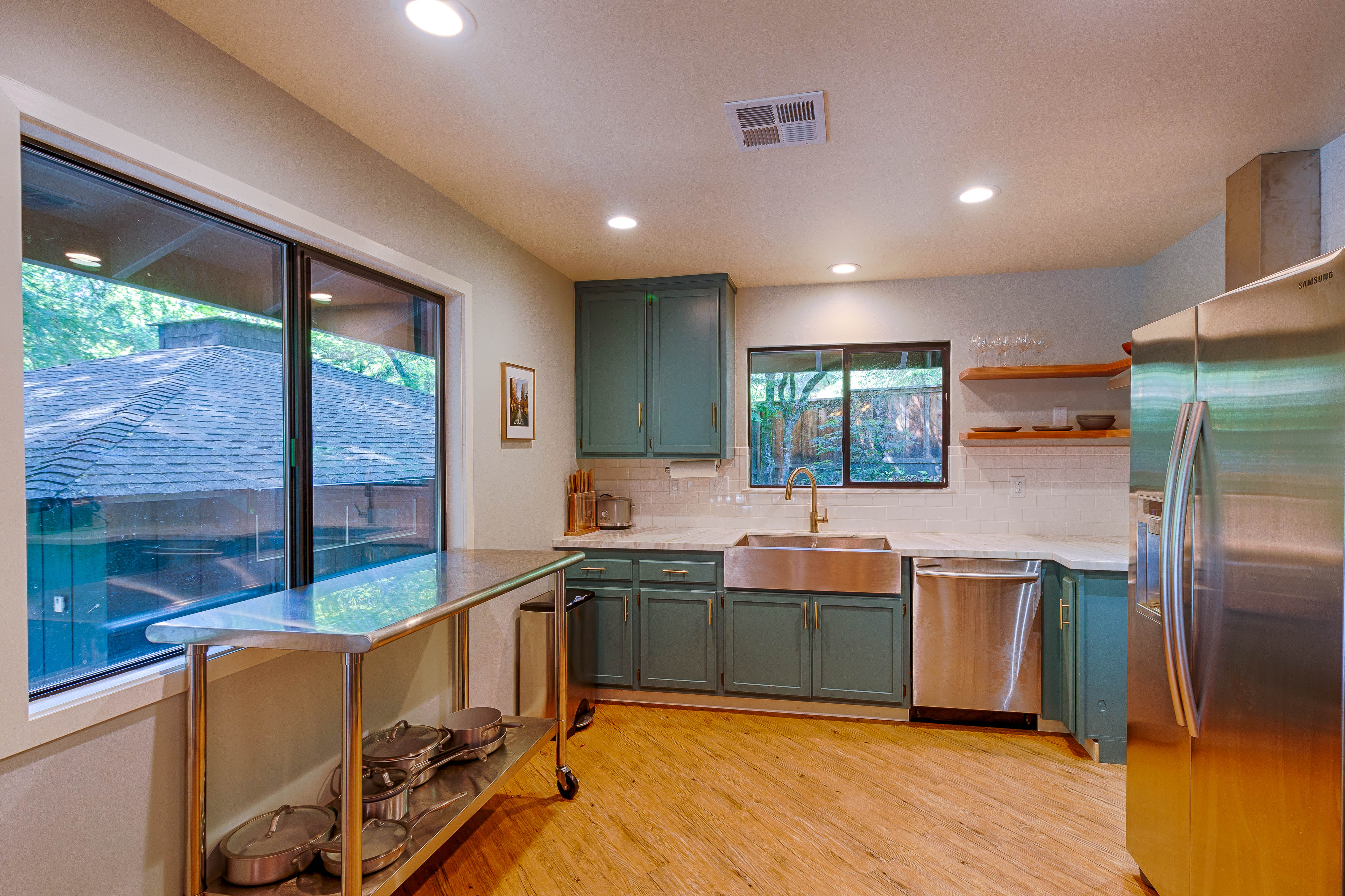 The quiet green kitchen with open shelves and stainless counters