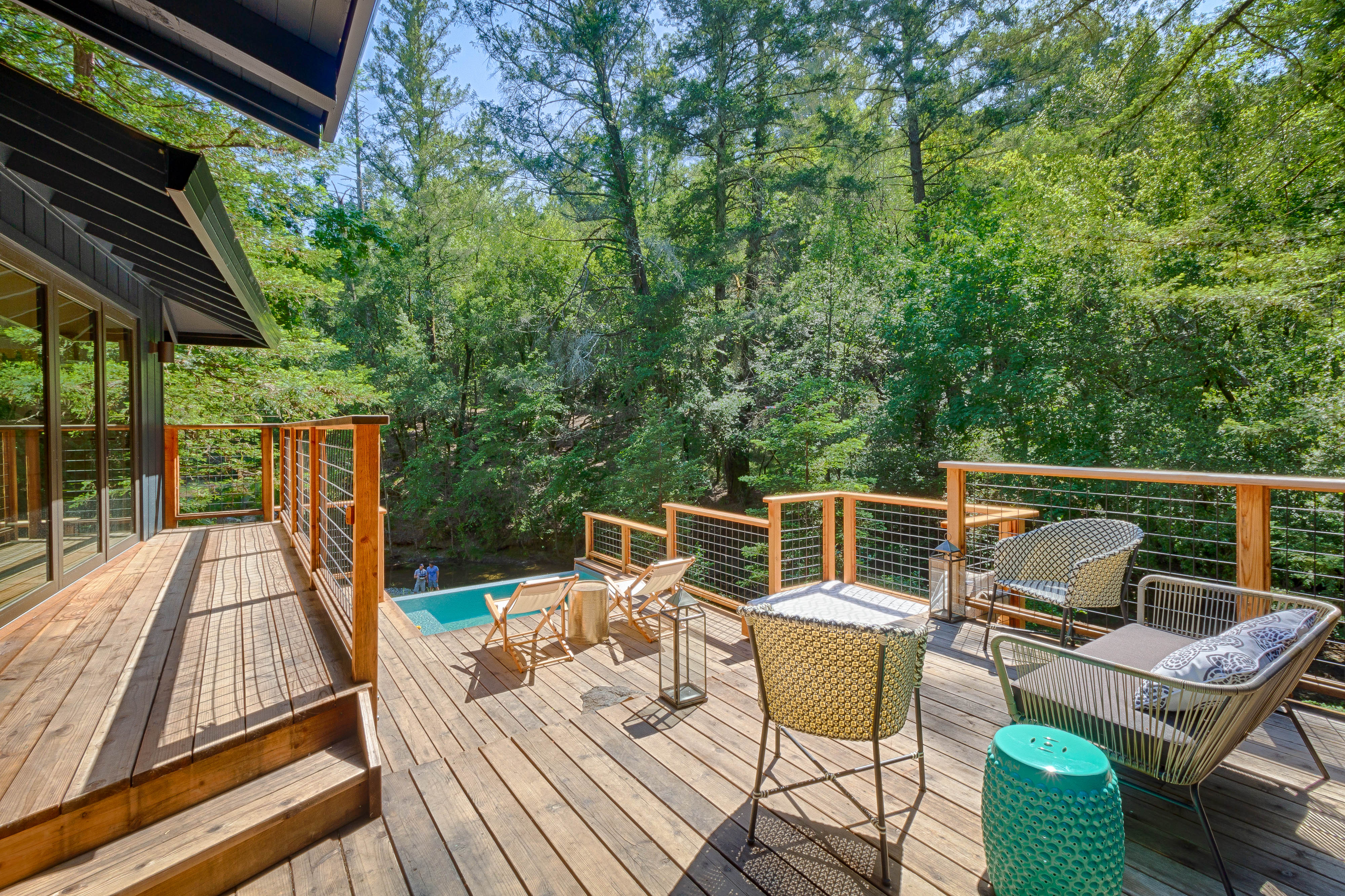 The creekside deck descending toward the plunge pool among the trees