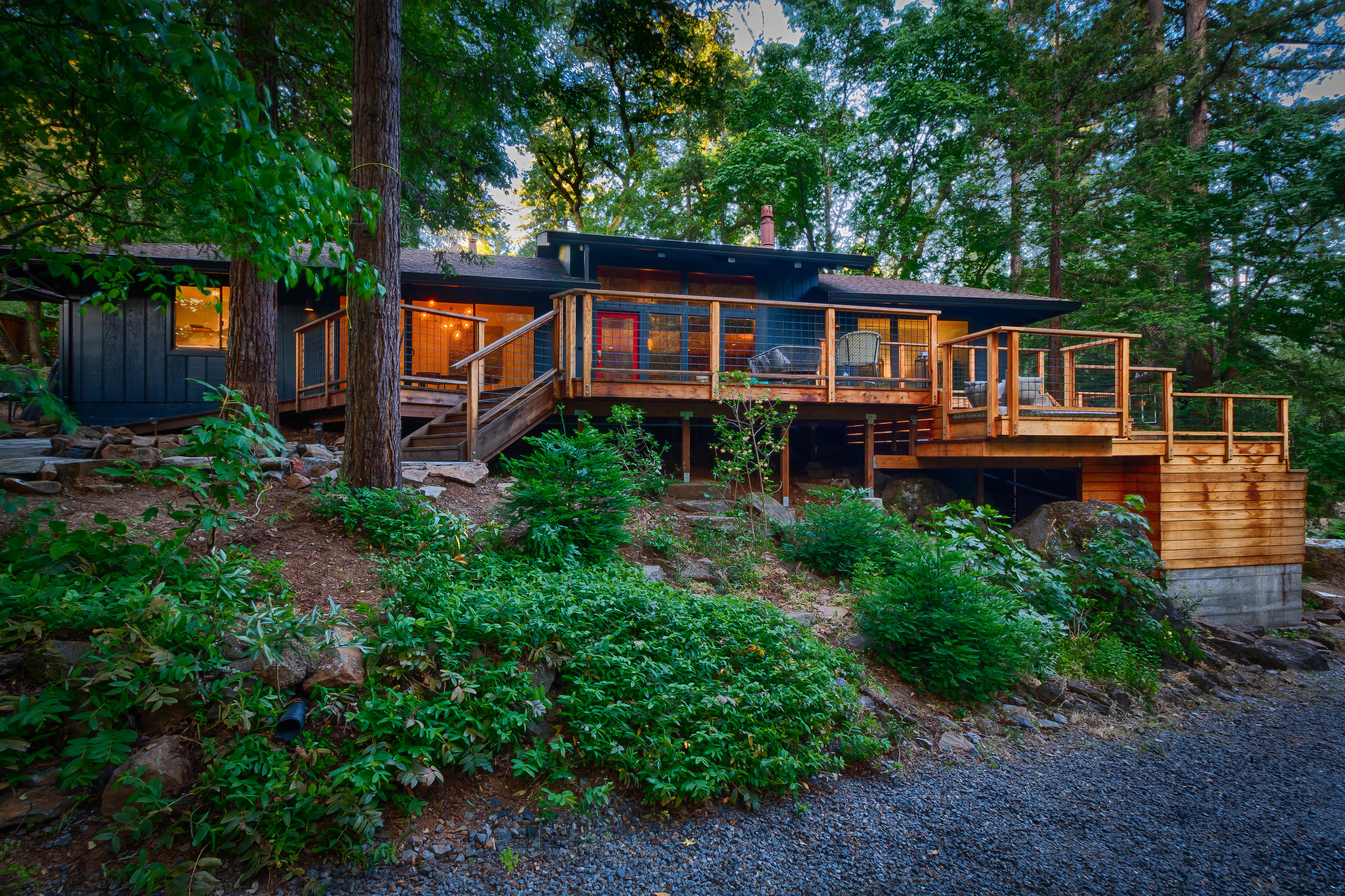 The restored dark cabin set into its redwood hillside above Mill Creek