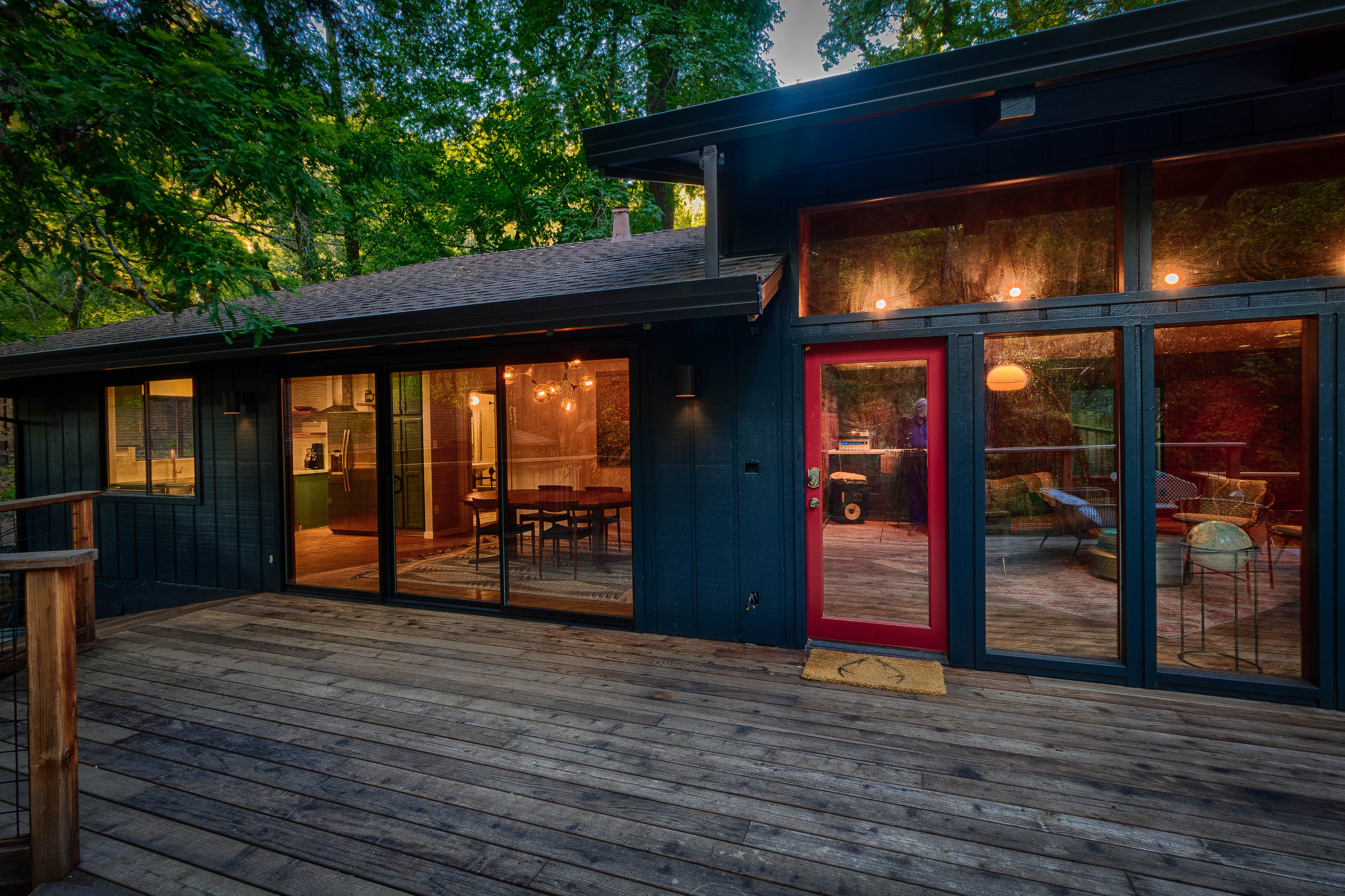 The dark Cosmico cabin glowing warmly among the redwoods at dusk